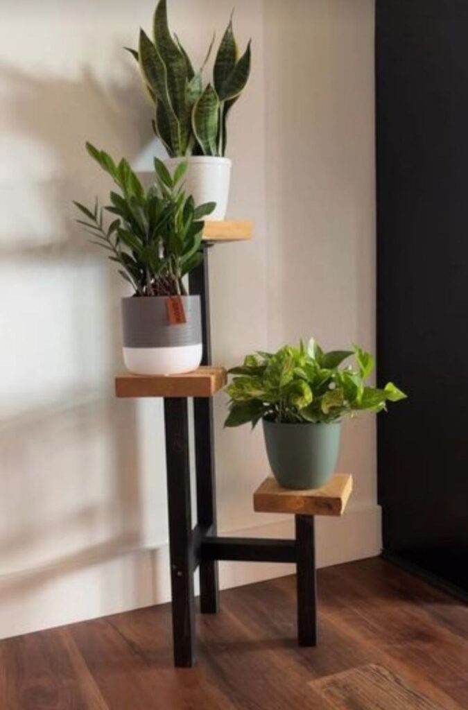 استند گلدان چوبی سه‌طبقه با پایه‌های فلزی، مناسب برای نمایش گیاهان دکوراتیو در دکوراسیون داخلی مدرن.